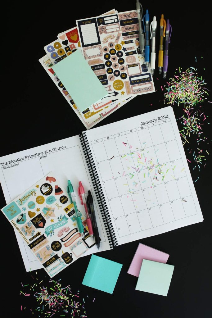 print and go planner open to january 2022 with post-its, pens, and stickers nearby with confetti.