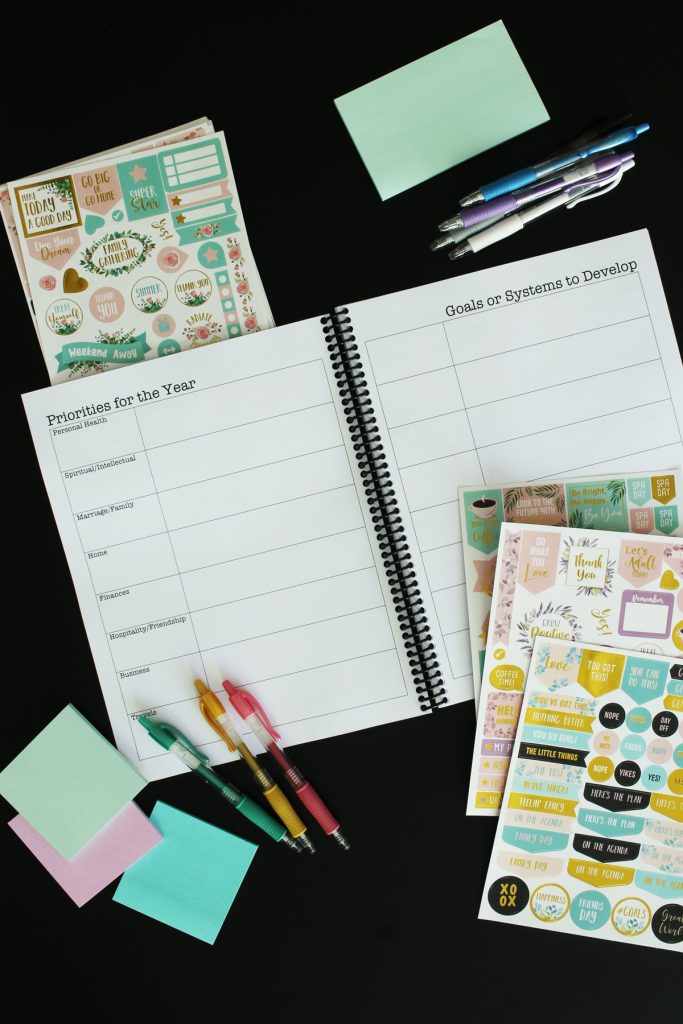 print and go planner open to yearly page with stickers, pens, and post-its on table nearby.