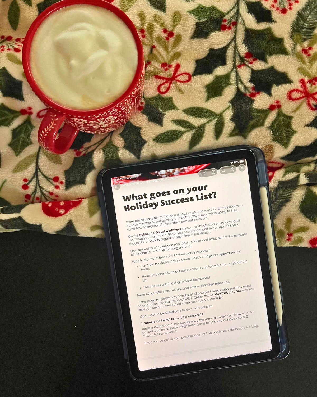 iPad open to a planning page in holiday success kit with holiday blanket and red mug of coffee.
