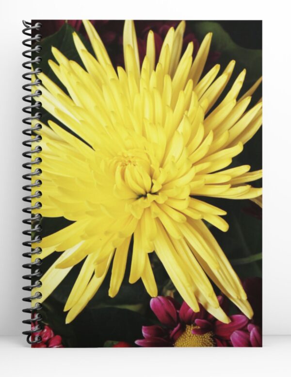 spiral notebook with black coil and a big yellow flower in the center.